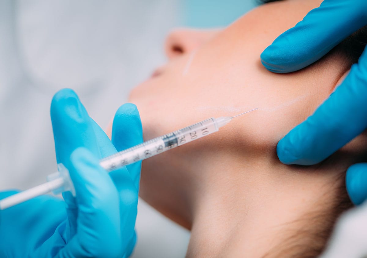 Woman receiving jawline filler to define and contour the lower face in Oakville