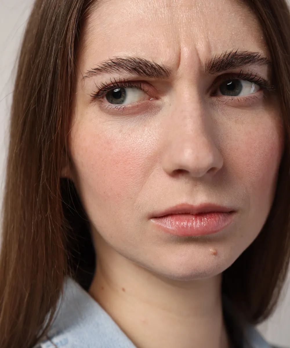 Woman frowning, showing the vertical 11 lines between the brows