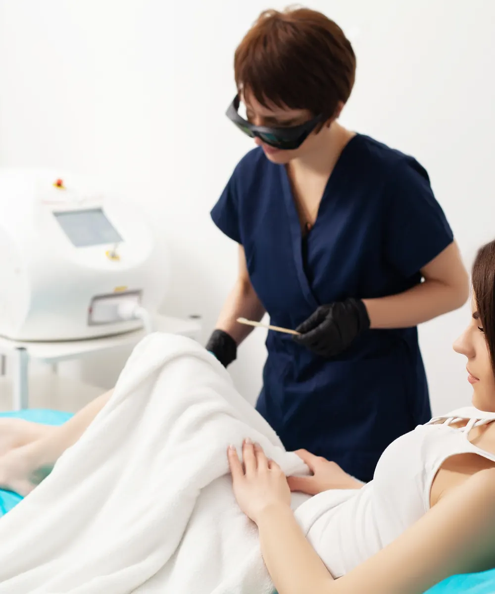 Woman receiving laser hair removal treatment in a clinic treatment room
