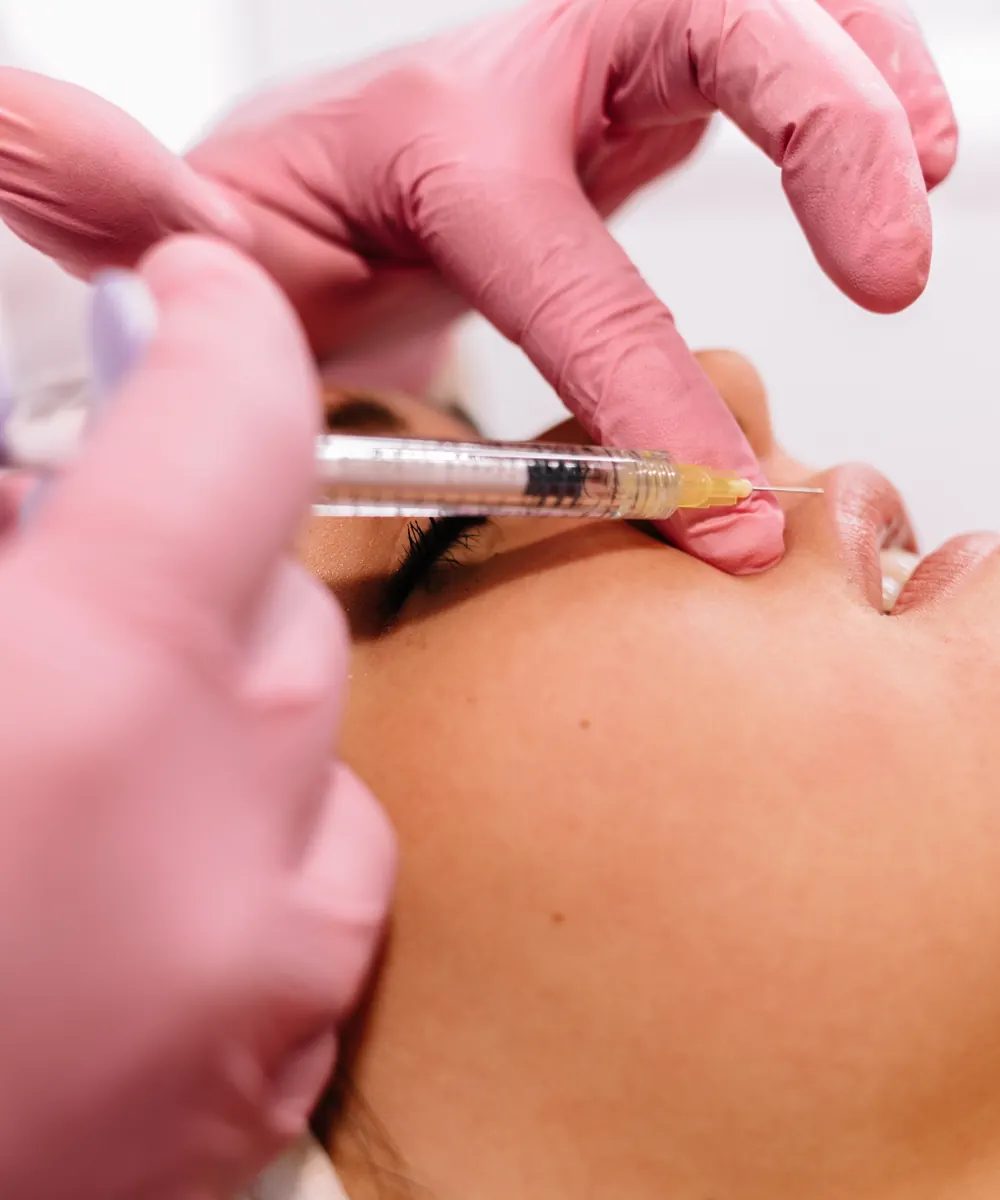 Practitioner performing a facial filler treatment in a clinic setting