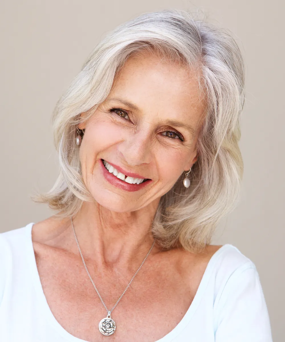 Woman in her forties looking at her reflection and assessing her cheeks and mid face