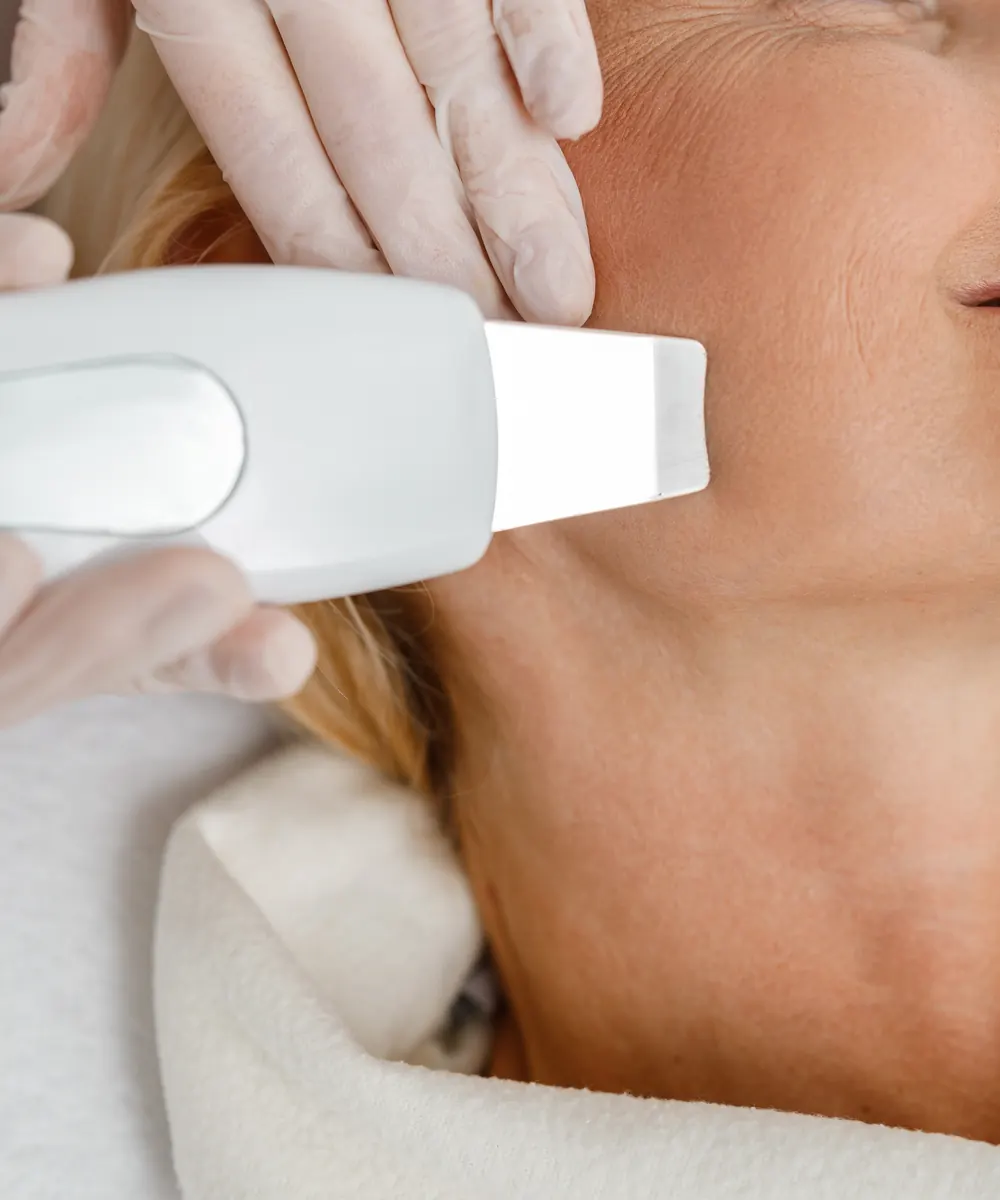 Ultrasound skin tightening handpiece being applied along the jawline in a clinic