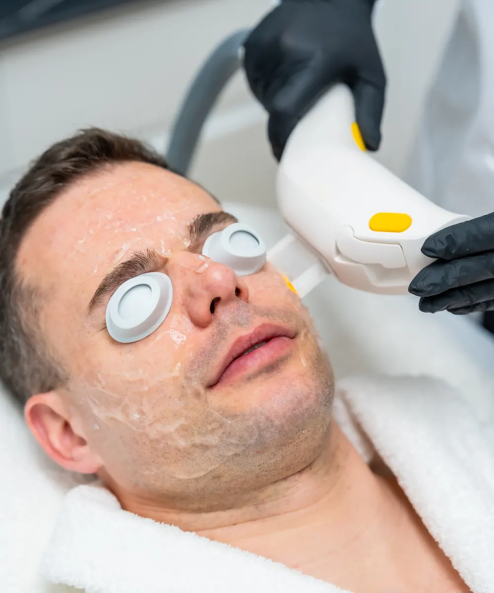 Man with eye shields and clear gel on his face during a light based facial treatment