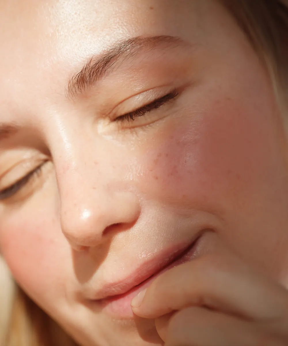 Close view of a relaxed face with soft rosy cheeks in warm natural light