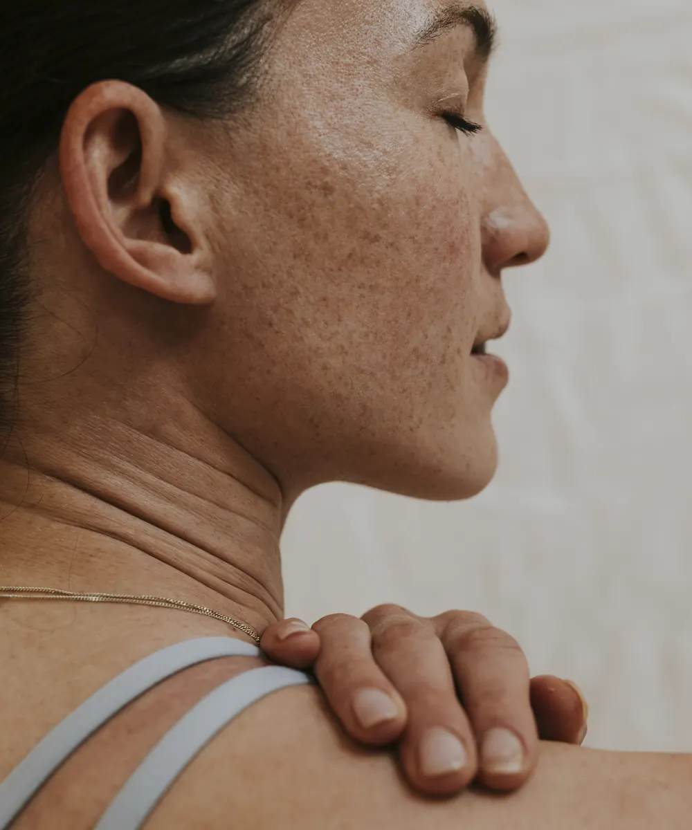 Profile of a woman with freckled face, neck and shoulder, her hand resting on the shoulder