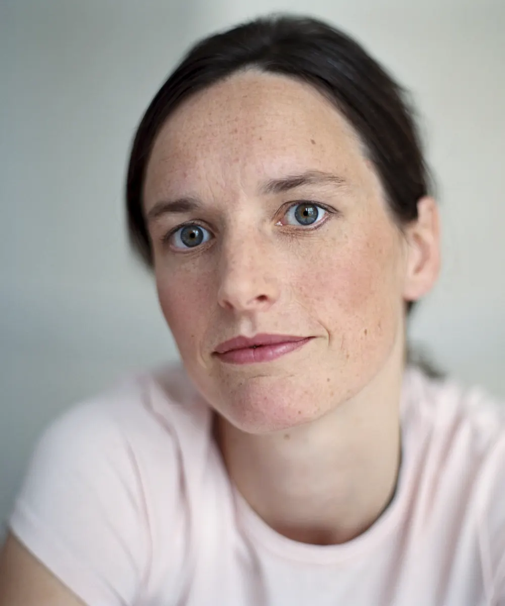 Woman in a pink tee with freckles and mild redness across her cheeks