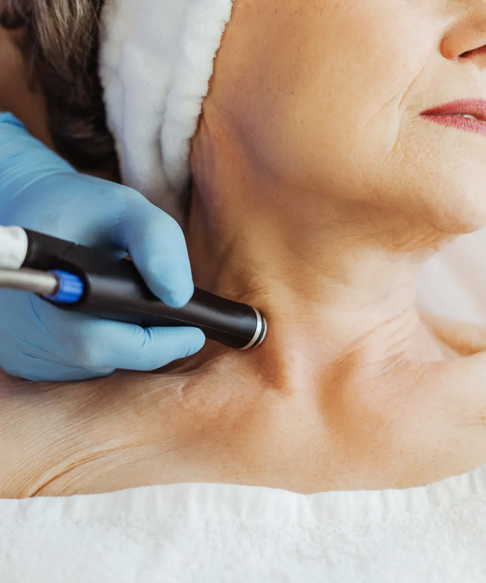 Gloved hand moves a smooth handheld device along the neck of a relaxed older woman