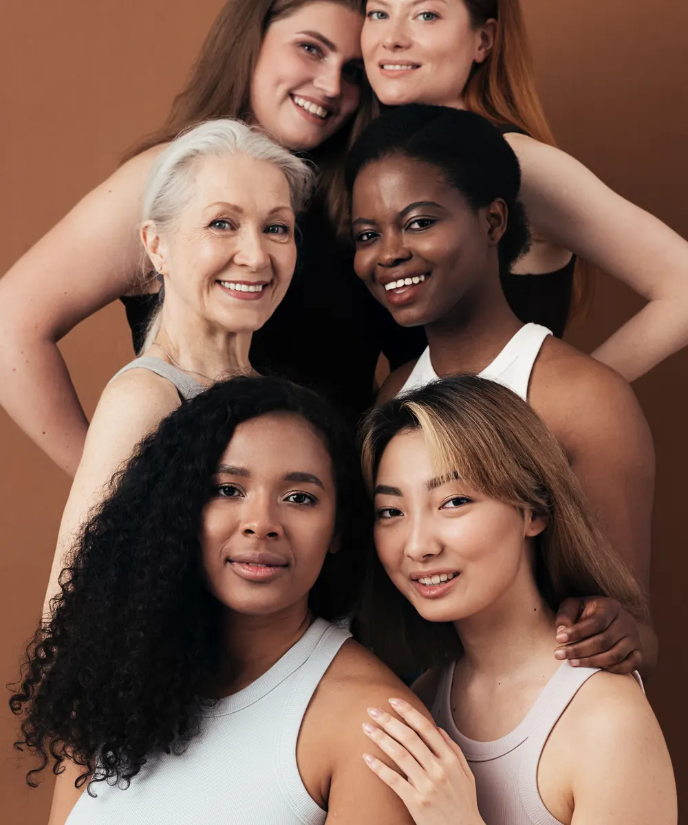 Six smiling women of different ages and skin tones posed closely together